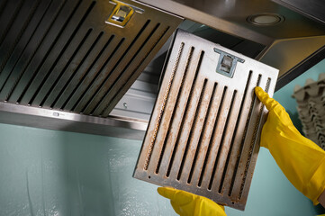 Housekeeping holding a stained filters of cooker hood before cleaning it. Clean your filters every two to three months, depending on your cooking habits.