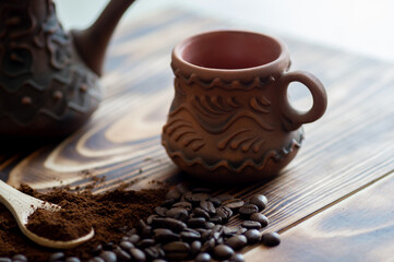 Ground and bean coffee in wooden spoon close-up and cup on wooden background
