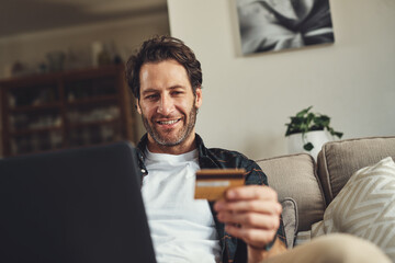 Man, home and smile on laptop with credit card on sofa for online shopping, payment and saving plan. Rewards, happy and couch in living room for internet banking, budget and investment or finance