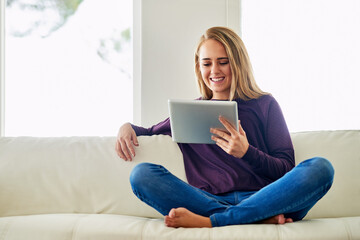 Reading, online and woman with tablet, smile and happy for romance ebook in lounge, chill and home. Living room, relax and girl on sofa, digital and entertainment of fiction with internet in app