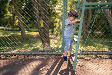 2 years old boy climbing ladder with hat in park.