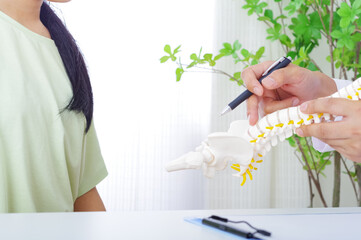 骨格模型で説明をする男性と患者の女性