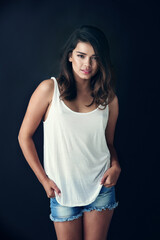 Woman, studio and confident for summer or fashion on dark background for fun, confidence and trends. Female person, isolated and portrait with smile for trendy clothes, outfit and style with shorts