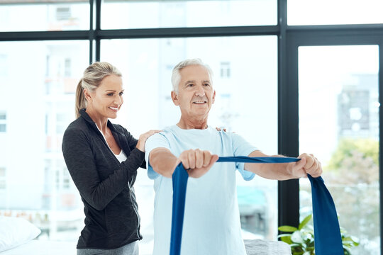 Mature, man and resistance band with woman or physiotherapist for physical therapy, mobility exercise and arthritis management. Geriatric physiotherapy, stretching arm and rehabilitation for recovery