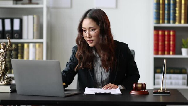 Female lawyer working on legal documents in the office, she is reading to check the agreement before signing the contract.