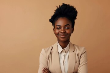 Obraz premium Smiling African woman posing confidently with folded arms stylishly dressed on beige background