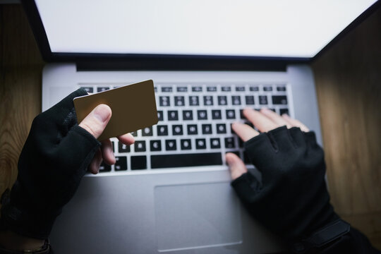 Laptop, credit card and hands of hacker for cyber crime, financial fraud and cloning for identity theft or breach. Person, dark and online for hacking or malware attack, phishing and account takeover