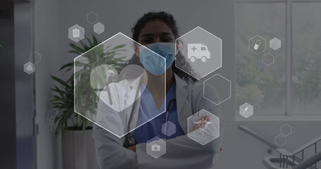 Image of digital icons data processing over biracial female doctor in face mask - Powered by Adobe