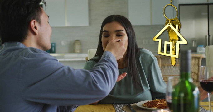 Image of gold house key and key fob over happy diverse couple eating at home - Powered by Adobe