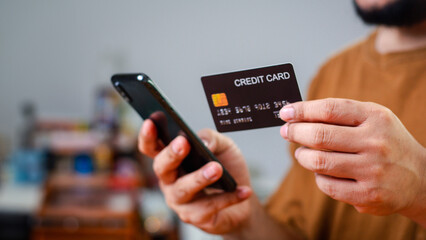 Man Using Smartphone Shopping Online Holding Credit Card Making Payment At Home. Mobile payment with wallet app technology. Internet Banking Application And E-Commerce, Digital money transfer