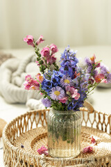 Still life with a bouquet of blue and pink wildflowers in a vase.