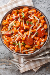 Gochujang Pasta combines al dente macaroni with a bold and fiery gochujang sauce closeup on the plate on the table. Vertical top view from above