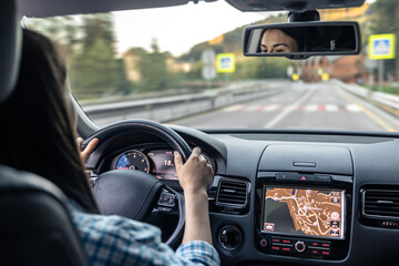 Woman driving a car, hands on the wheel close-up, view from the back to the road.