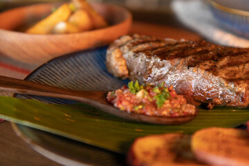Colombian baby beef steak with hogao sauce and arepas on a banana leaf