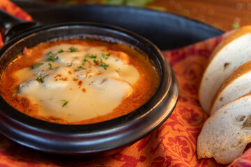 Close-up of a rustic bowl of Colombian tomato soup with melted cheese