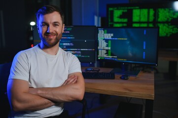Male programmer working on desktop computer at white desk in office
