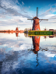 Windmills in Kinderdijk museum reflected in the calm waters of Holland canal, UNESCO World Heritage Site. Stunning summer scene of Netherlands countryside, Europe. Traveling concept background.