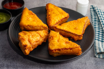 Selective Focus of Bread pakora is a popular Indian street food made with bread, stuffed with spicy potato filling, coated in chickpea flour, and deep-fried.