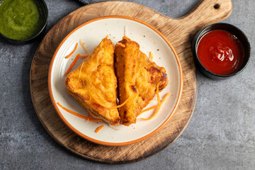 Selective Focus of Bread pakora is a popular Indian street food made with bread, stuffed with spicy potato filling, coated in chickpea flour, and deep-fried.