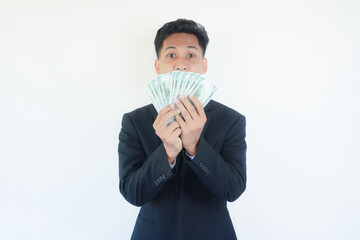 Winner! Young rich happy Asian man in suit holding money dollar bills and wallet with surprise isolated over white wall background.