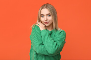 Young woman hugging herself on orange background