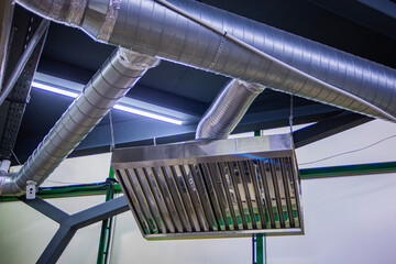 Stainless steel exhaust hood with grease trap close-up in a large industrial kitchen in the production of semi-finished products