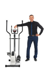 Mature businessman with exercising bike on white background