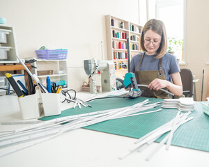 Obraz premium Woman tanner processes the edges of a leather belt in a workshop. 