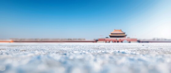   a distant building with snow-covered ground and a blue sky behind it