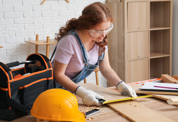 Female carpenter measuring plank width with square ruler in workshop