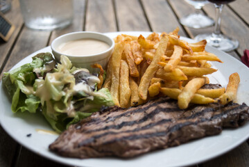 closeup of beefsteak, french fries and salad at the restaurant