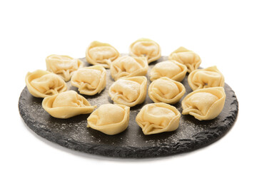 Black board with raw dumplings on white background