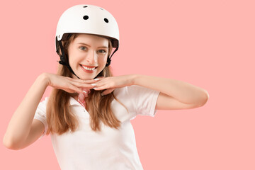 Beautiful young woman in helmet on pink background