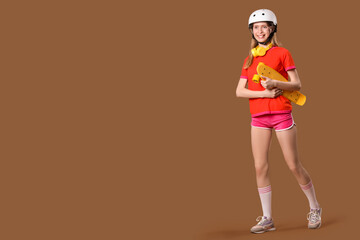 Beautiful young woman in helmet with skateboard on brown background