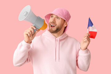 Young man with flag of France and megaphone on pink background