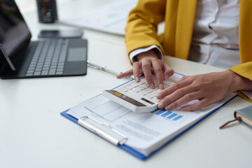 Young businesswoman, female office worker, calculator to calculate the financial results of the company in the office and work, tax, accounting, statistics and analytical research concepts.