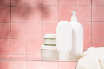 Bathroom with Cosmetic products at glass shelf at pink background.