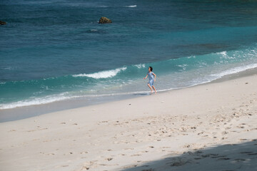 Little girl running along the seashore at Banyuwangi beach, alone.