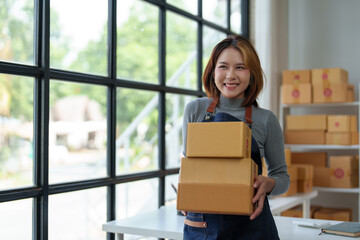 Small Business Startup, SME Owner, Independent Female Entrepreneur Stands Holding Parcel Boxes and Verifies Online Orders to Prepare Packaging Boxes to Sell to Customers. Online SME Business Ideas.