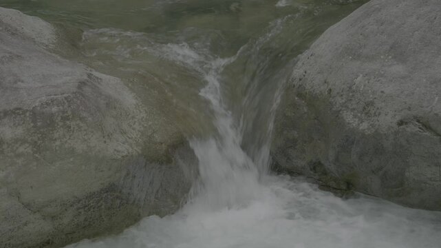Close-up of converging waterfalls flowing between rocks.  F-Log2 footage, perfect for colorists and Image editors..F-Log2, MOVH.265, All-I 422, 10bit, 360Mbps..