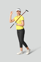 Beautiful female golfer on grey background