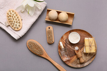 Composition with wooden tray, massage body brushes, sea salt, wooden massage balls and soap bar on grey background