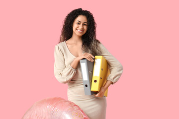 Happy female office worker with inflatable ring and folders on pink background. Summer vacation...