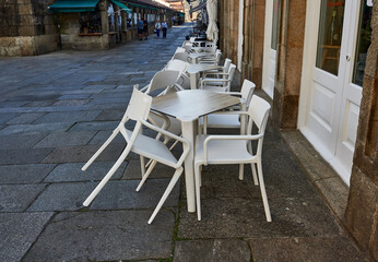 empty plastic tables and chairs on the street next to the closed bar
