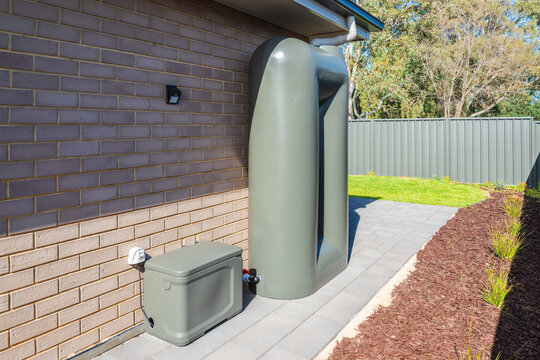 Rain water tank with pump box connected on the backyard of new suburban house in South Australia