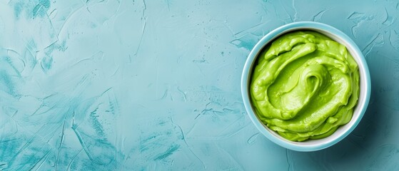 Obraz premium A blue backdrop features a tablecloth in shades of white and blue Atop it sits a filled bowl of vibrant green guacamole