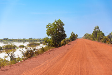 Naklejka premium Country dirt road of red sand in Cambodia with bikes