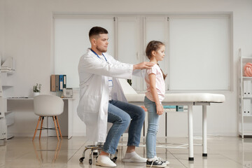 Male pediatrician examining little girl in clinic