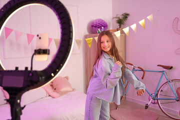 Teenage blogger dancing while recording video in bedroom