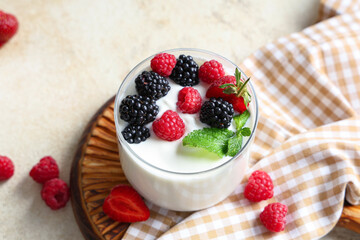 Glass of tasty yogurt with fresh raspberries and blackberries on white background